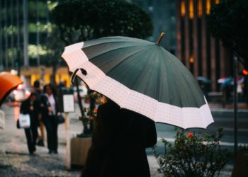 Selective Focus Photography Of Woman Walking On Street While Holding Umbrella